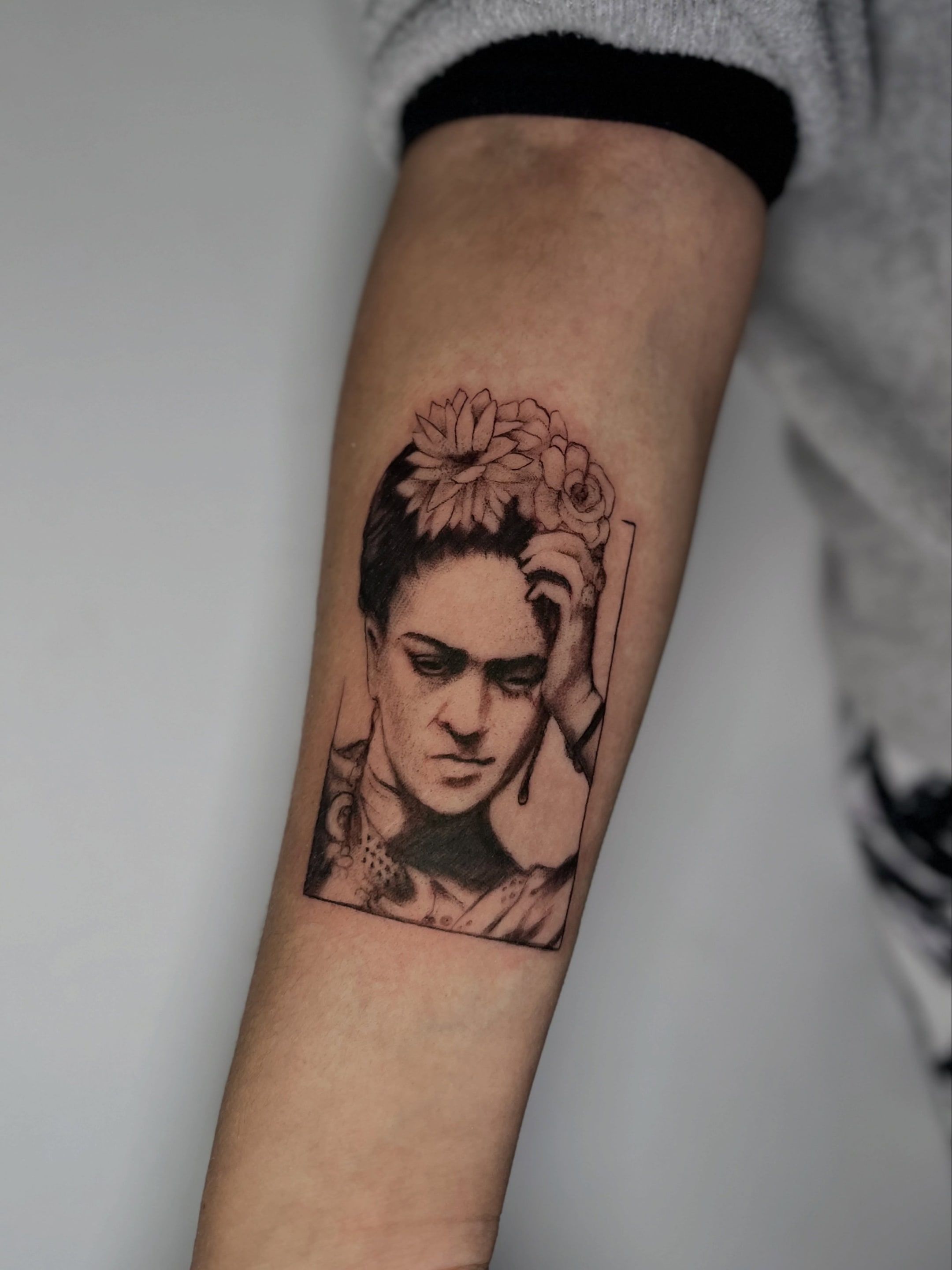 Retrato de Frida Kahlo con flores en el pelo, enmarcado en un rectángulo, en el antebrazo