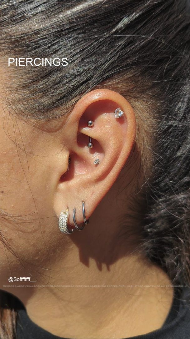 Oreja con piercings en rook, flat, conch y aros en el lóbulo