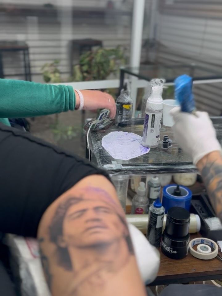 Mesa de trabajo del estudio con tintas y máquina, y un retrato en proceso en primer plano