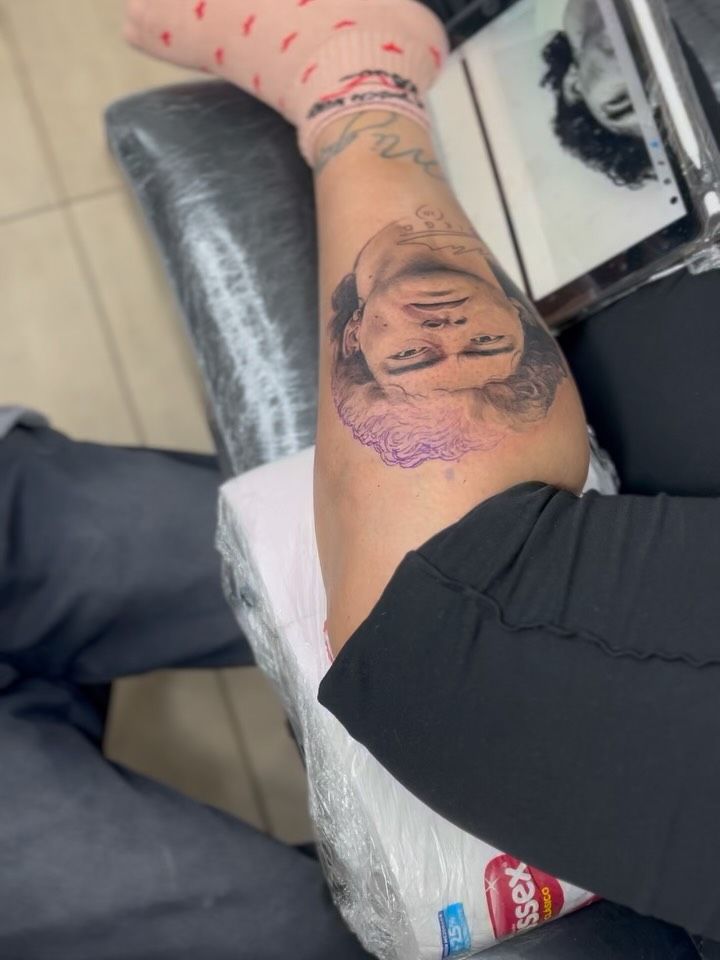 Retrato a medio tatuar en el gemelo junto a la tablet con el diseño de referencia